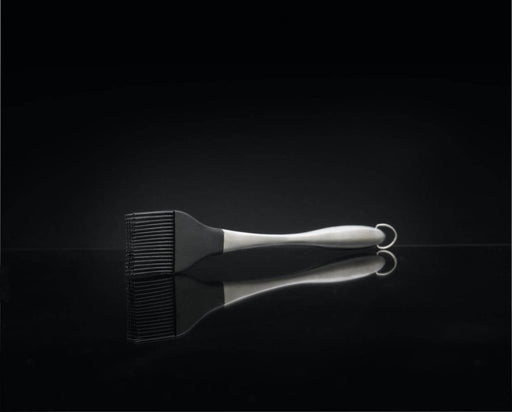 Black barbecue brush on a reflective black surface with a dark background